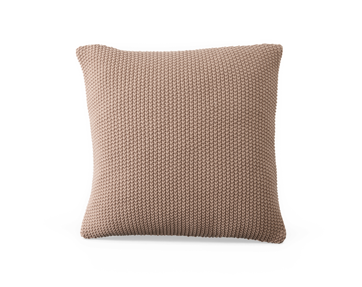 Beige strikket pyntepude med grov tekstur, frilagt på hvid baggrund.