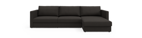 Mørkegrå hjørnesofa med chaiselong til højre på sort baggrund.