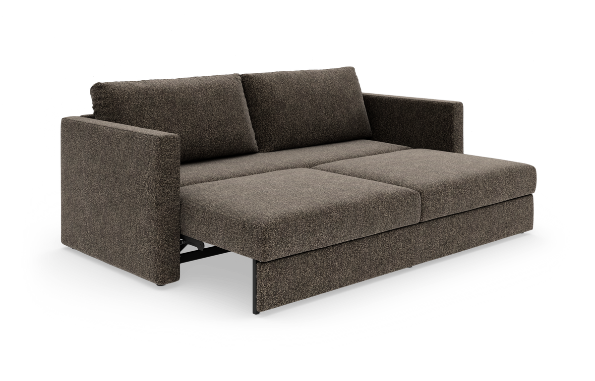 Brun sovesofa i stof, vist delvist udfoldet med brede armlæn og to ryghynder.