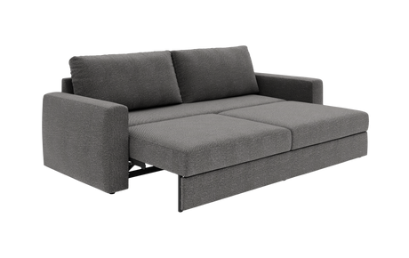 Grå sovesofa i stof, vist i udfoldet sengestilling i studieopsætning fra trekvart vinkel.