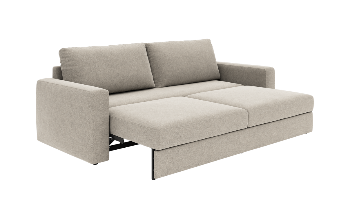 Beige sovesofa i stof, trukket ud til seng med to ryghynder og lige armlæn, fritlagt på hvid baggrund i skrå frontvinkel.