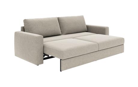 Beige sovesofa i stof, trukket ud til seng med to ryghynder og lige armlæn, fritlagt på hvid baggrund i skrå frontvinkel.