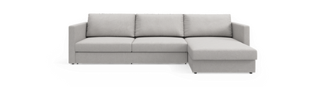 Lysgrå hjørnesofa med chaiselong i højre side, tre ryghynder og lige armlæn, frilagt mod sort baggrund.