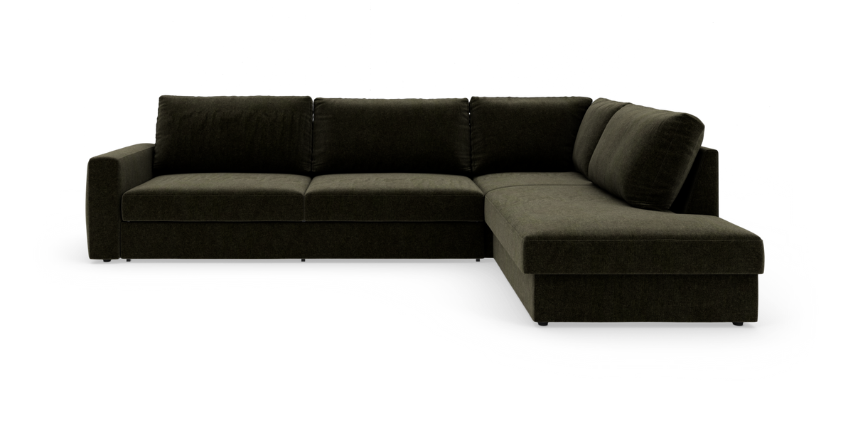 Mørkegrøn L‑sofa med chaiselong til højre, fotograferet i studie mod hvid baggrund.