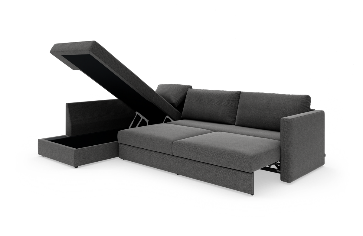 Mørkegrå sovesofa med chaiselong og opklappelig opbevaring, fotograferet skråt forfra mod hvid studiebaggrund.