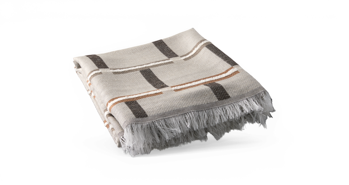 Sammenfoldet plaid med tern i beige og grå med brune detaljer og frynset kant.