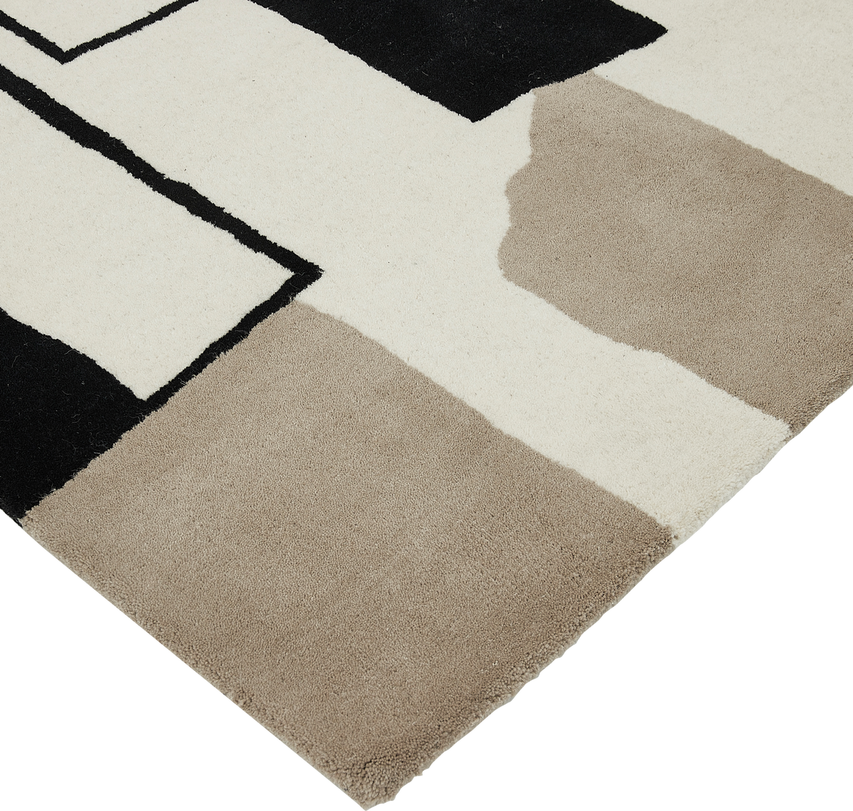 Hjørnevisning af et tæppe med abstrakt geometrisk mønster i sort, hvid og beige.