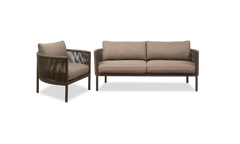 Brun loungestol med rund ram, flettede sider og beige hynder, fotograferet i 3/4‑vinkel.