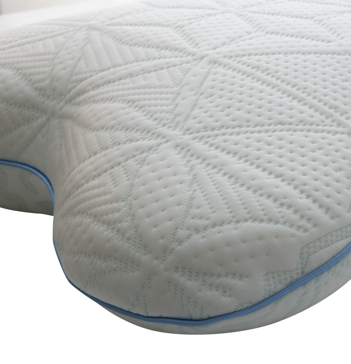 Nærbillede af en hvid ergonomisk pude med mønstret, quiltet overflade og blå piping.