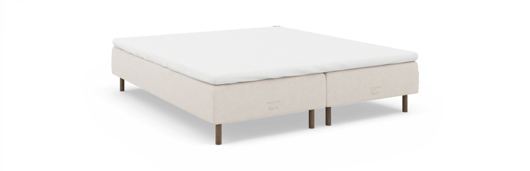 Beige kontinentalseng med hvid topmadras, træben og mærkningen 'nocturne by TEMPUR'.
