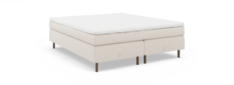 Beige kontinentalseng med hvid topmadras og træben, mærket “nocturne by TEMPUR”, fotograferet i vinkel på neutral baggrund.
