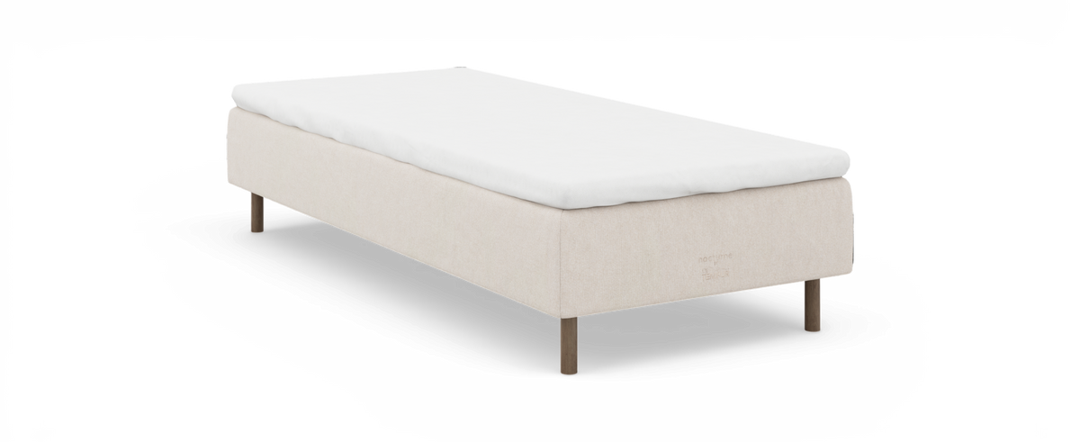 Beige sengebund med hvid topmadras; nocturne by TEMPUR på siden.
