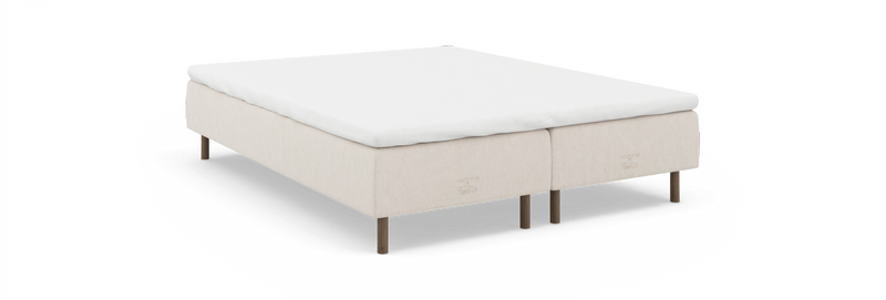 Beige kontinentalseng med hvid topmadras og træben, mærket 'nocturne by TEMPUR' på siden._ps