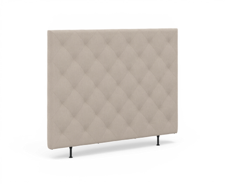 Beige polstret sengegavl med diamant-quiltet tuftning og slanke sorte ben.