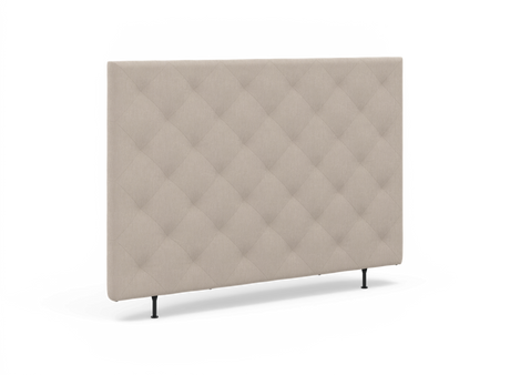 Beige, quiltet sengegavl med diamantmønster og slanke sorte ben, fotograferet i let vinkel på hvid baggrund.