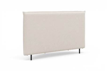 Beige, stofbetrukket sengegavl med slanke sorte ben, fotograferet mod hvid baggrund.