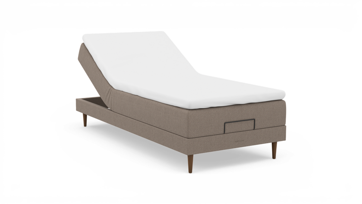Beige justerbar seng med hvid topmadras og træben, nocturne-logo på soklen.