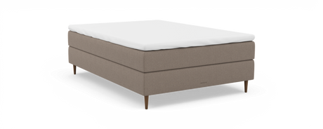 Beige polstret enkeltseng med hvid topmadras, træben og “nocturne”-branding, frilagt på sort baggrund.