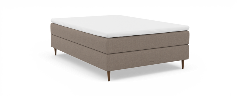 Beige polstret enkeltseng med hvid topmadras, træben og “nocturne”-branding, frilagt på sort baggrund._ps