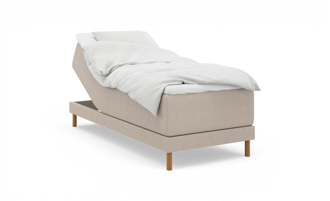 Beige elevationsseng med hævet hovedende, hvidt sengetøj og træben, frilagt på hvid baggrund.