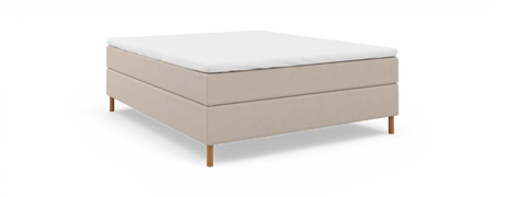 Beige kontinentalseng med hvid topmadras, frilagt mod sort baggrund i skrå frontvisning.