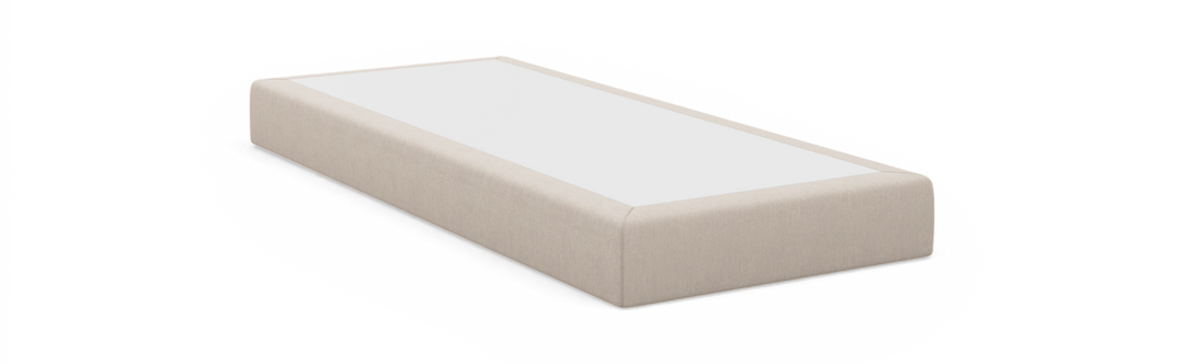 Beige polstret sengebund/box med hvid topplade, lav rektangulær profil set i trekvart vinkel.