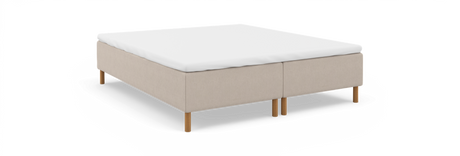 Beige kontinentalseng-base med hvid topmadras og runde træben, frilagt på hvid baggrund.