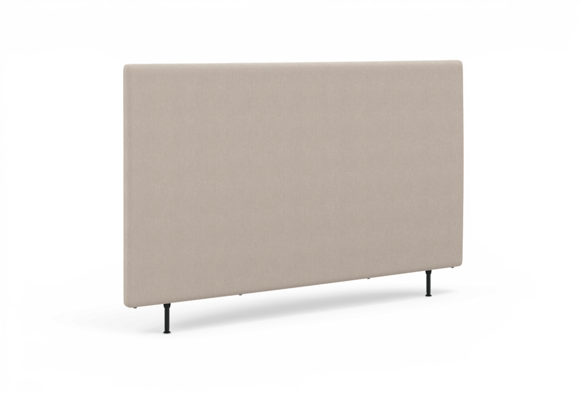 Beige sengegavl i stof med slanke sorte ben, fotograferet i studie i let skrå vinkel.