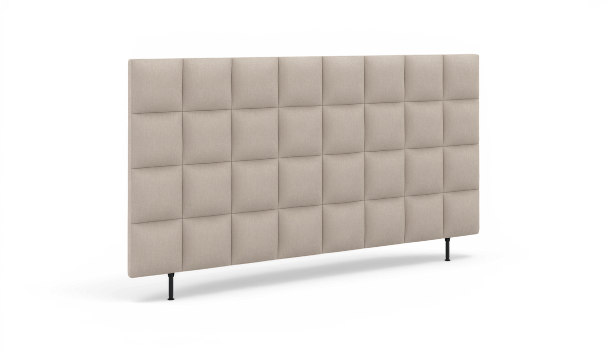Beige polstret sengegavl med kviltet ternmønster og slanke sorte ben, frilagt på hvid baggrund.