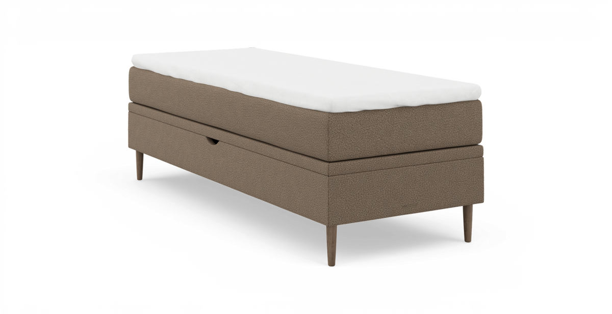Enkel enkeltseng/boxmadras i beige polstret stof med hvid topmadras og slanke træben.