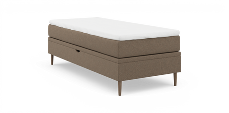 Enkeltseng i beige stof med hvid topmadras og slanke træben, frilagt på hvid baggrund.