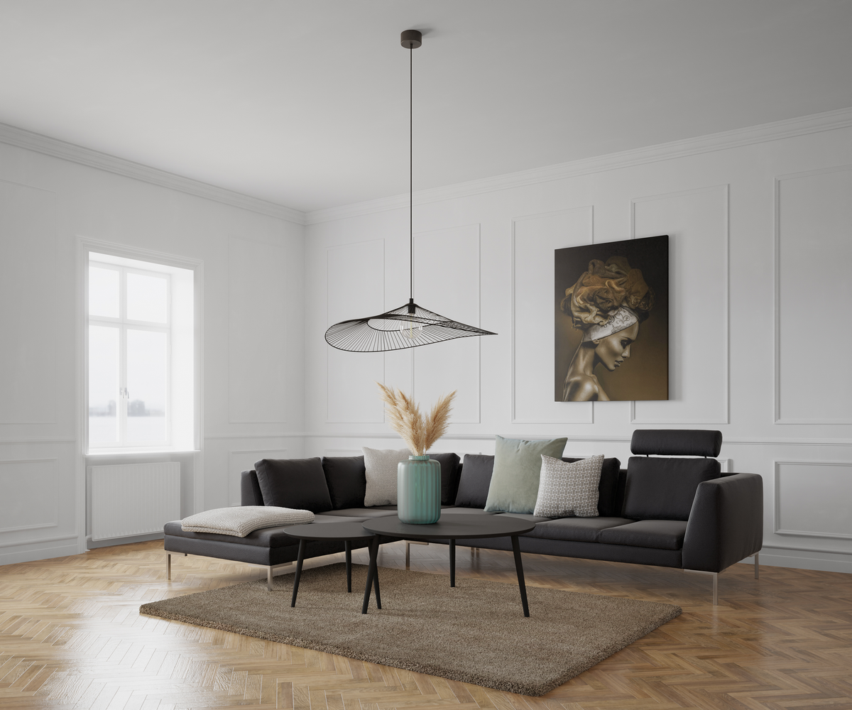 Lys skandinavisk stue med mørk modulsofa, lave sorte sofaborde, grøn vase med pampasgræs, vægpaneler og sildebenstrægulv; luftig pendellampe og kunst på væggen ved vindue i dagslys.
