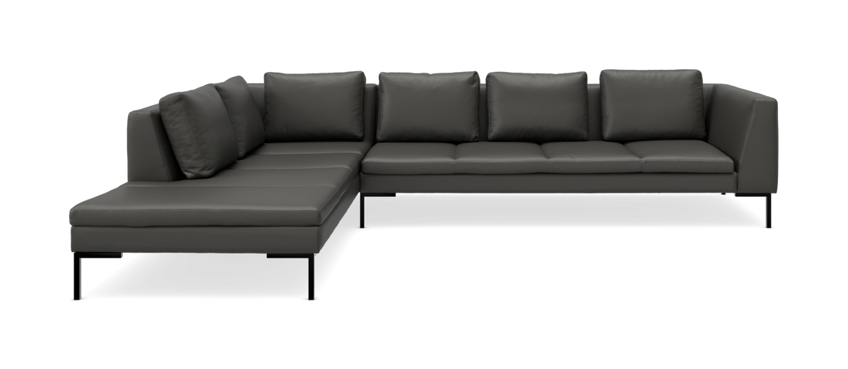 Mørkegrå L-formet modulsofa med chaiselong til venstre og slanke sorte ben, fritlagt på neutral baggrund.