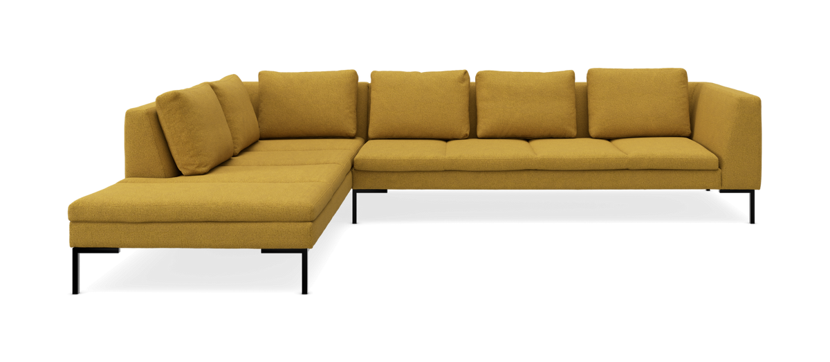 Sennepsgul L-formet hjørnesofa med chaiselong, løse ryghynder og sorte metalben.