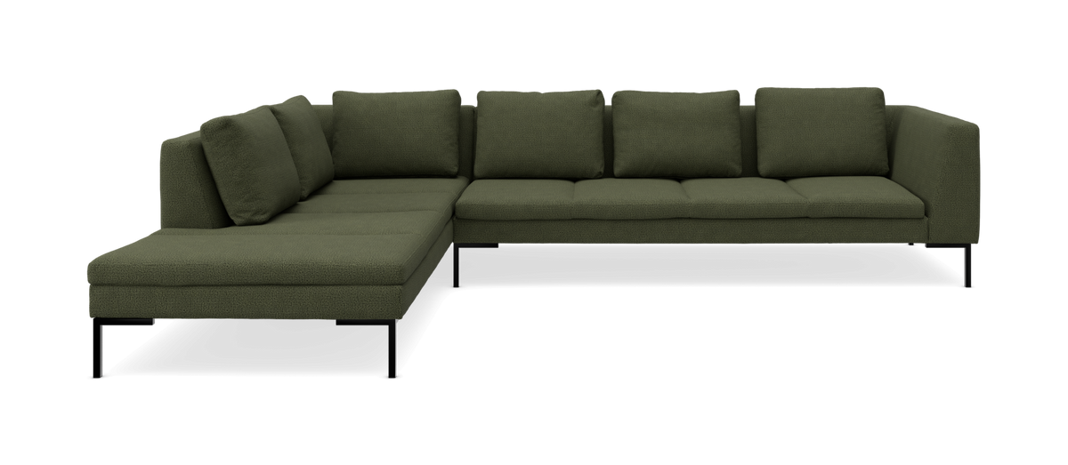 Grøn L‑formet modulsofa med chaiselong til venstre og slanke sorte ben, frilagt produktbillede.