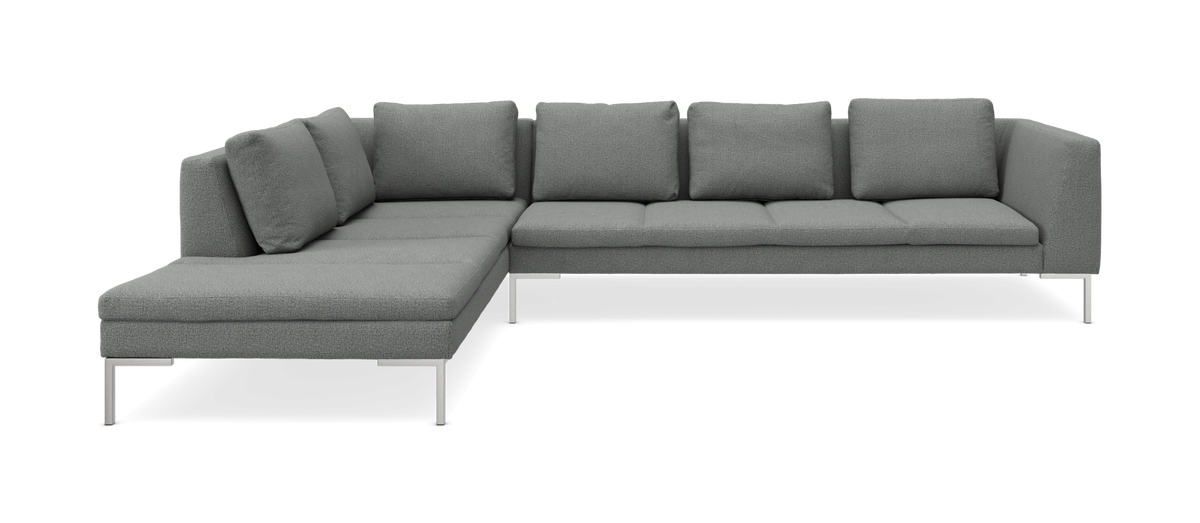 Grå L-formet hjørnesofa med chaiselong til venstre, metalben og løse ryghynder, frilagt på hvid baggrund.