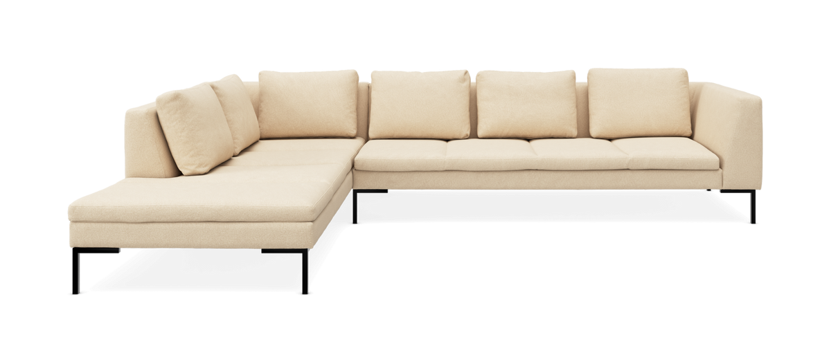 Beige hjørnesofa med venstrevendt chaiselong, fem ryghynder og slanke sorte metalben, frilagt på hvid baggrund.