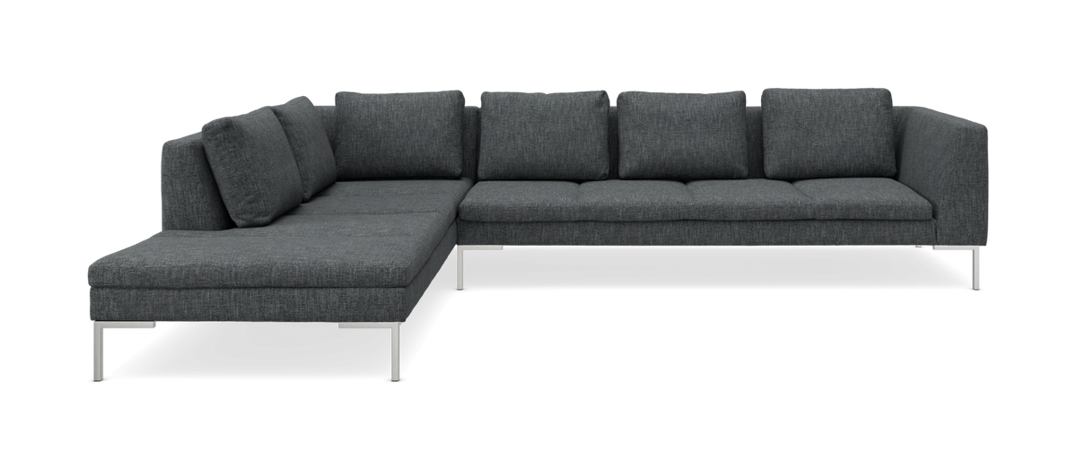 Mørkegrå L‑formet modulsofa med metalben, frilagt på sort baggrund.
