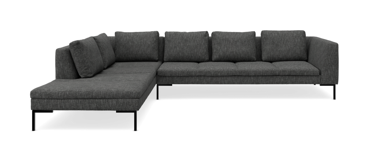 Mørkegrå hjørnesofa med chaiselong til venstre på slanke sorte ben.
