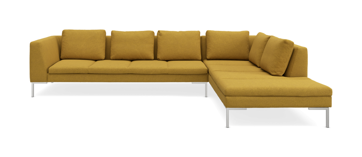 Sennepsgul L-formet hjørnesofa med metalben i frontvinkel.