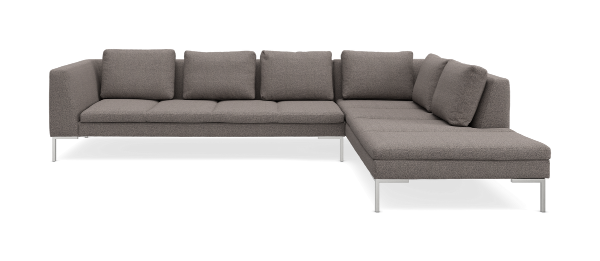 Grå L-formet hjørnesofa med chaiselong og metalben, seks ryghynder, frilagt på hvid baggrund.