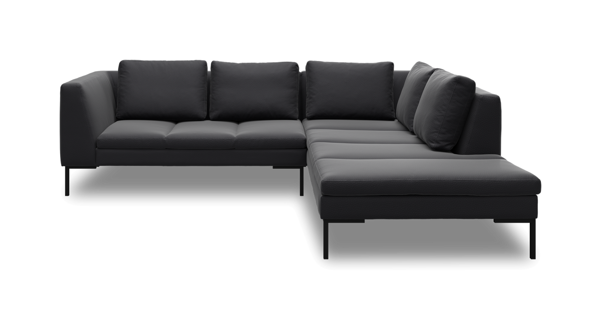 Mørkegrå L‑formet modulsofa med slanke sorte ben, frilagt på sort baggrund.
