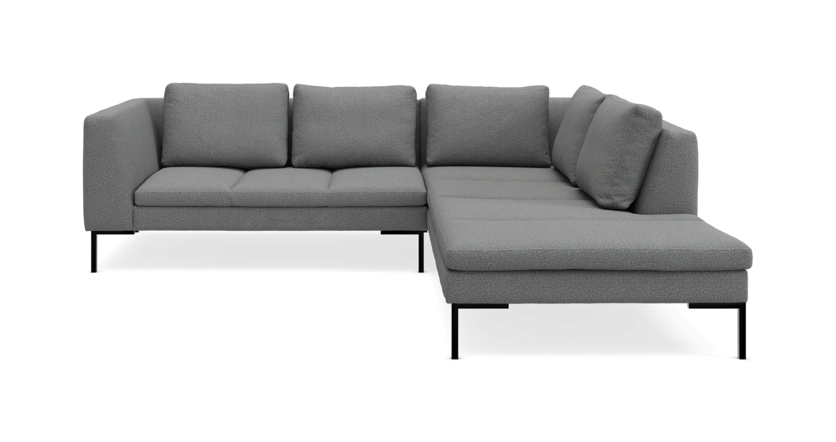 Grå L-formet hjørnesofa med chaiselong til højre på slanke sorte ben.