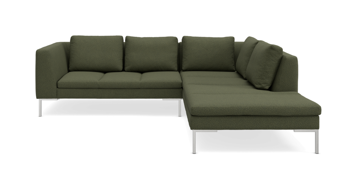 Grøn L‑formet modulsofa med chaiselong og metalben, frilagt i studie.