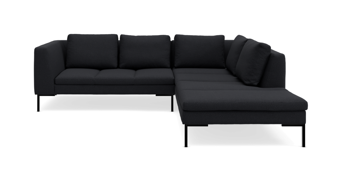 Mørkegrå modul-hjørnesofa med chaiselong til højre på slanke sorte ben.