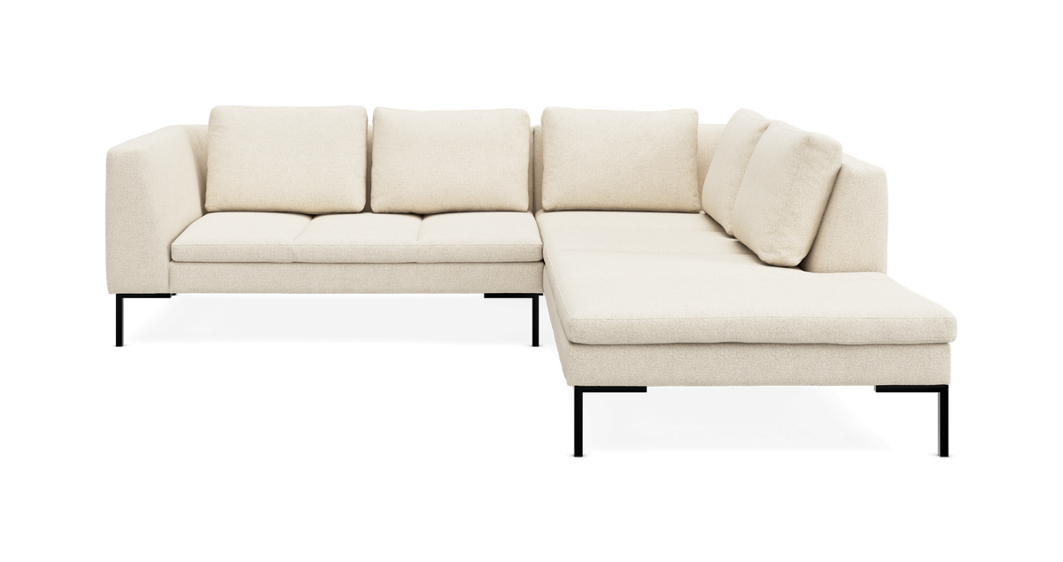 Beige L-formet hjørnesofa med chaiselong til højre på sorte metalben, frilagt på hvid baggrund.