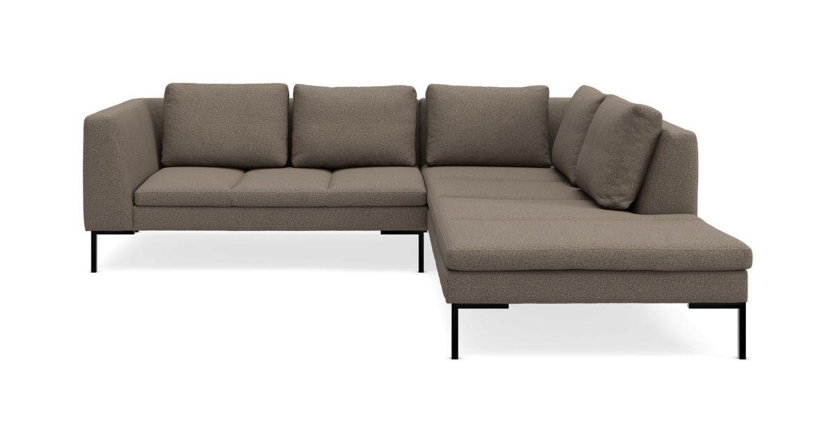 Modul hjørnesofa med chaiselong til højre i beige/taupe stof med slanke sorte ben, frilagt på hvid baggrund.