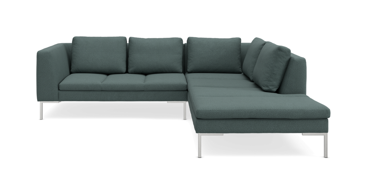 Mørk grøn/blågrøn L-formet hjørnesofa med chaiselong til højre og metalben, frilagt på hvid baggrund.