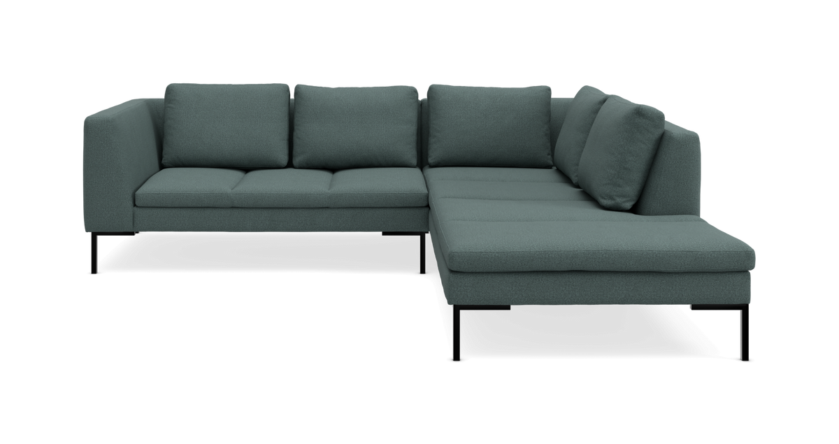 Grøn L-formet hjørnesofa med chaiselong til højre og slanke sorte ben.