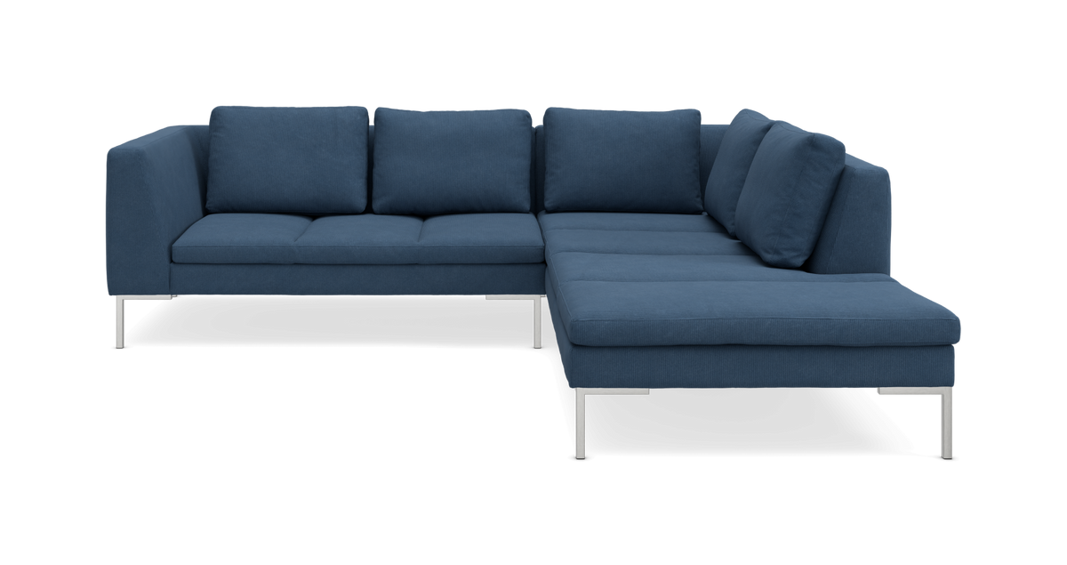 Blå L-formet hjørnesofa med metalben, frilagt på hvid baggrund, frontvisning.